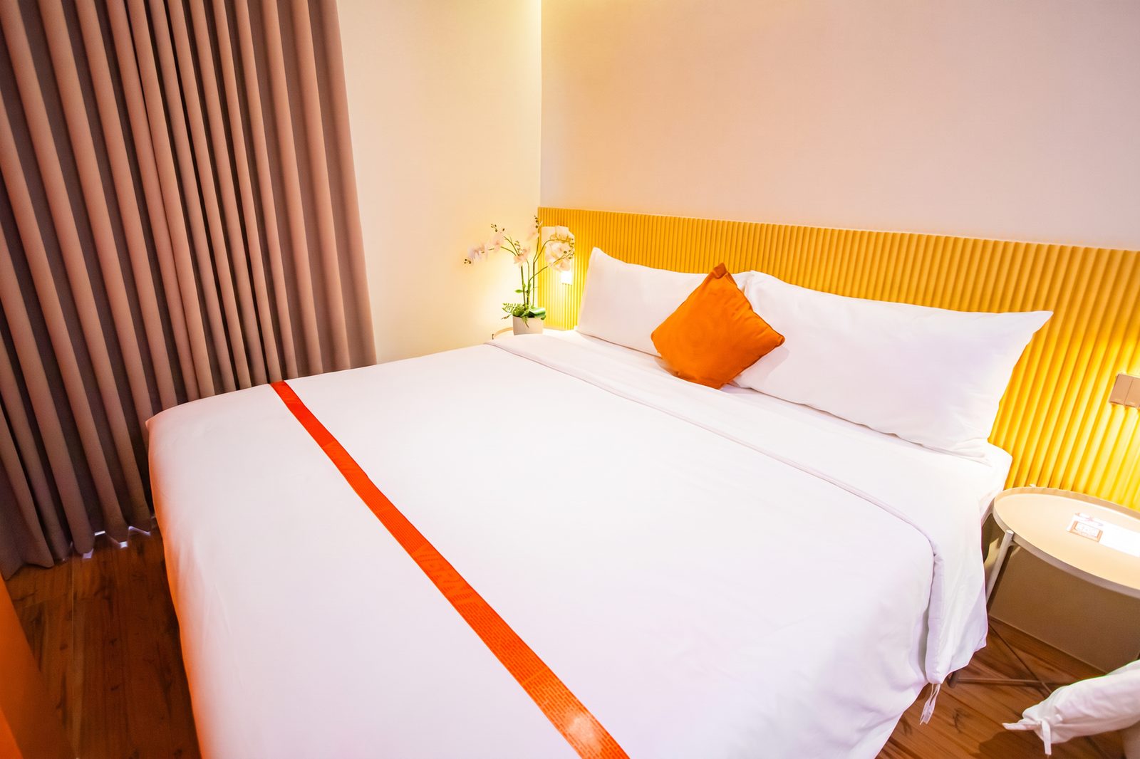 Premium Vibe queen room with orange bed runner and gold headboard